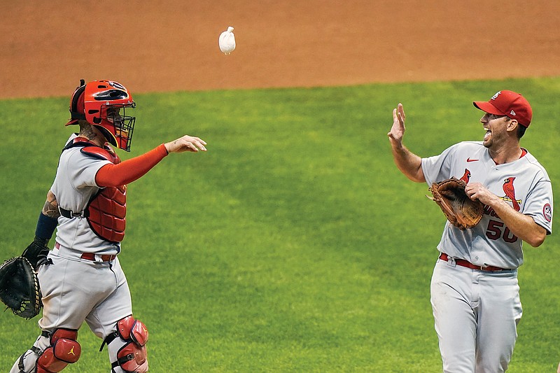 Cardinals catcher Yadier Molina throws pitcher Adam Wainwright a rosin bag after a 4-2 win against the Brewers in the first game of Wednesday's doubleheader in Milwaukee.