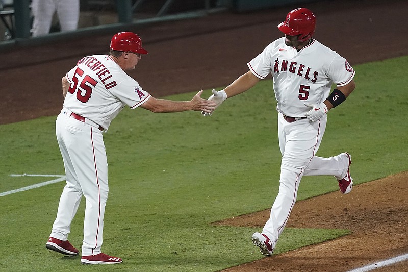 Albert Pujols is greeted by Angels third base coach Brian Butterfield as he rounds the bases on a solo home run during the fifth inning of Friday night's game against the Rangers in Anaheim, Calif.