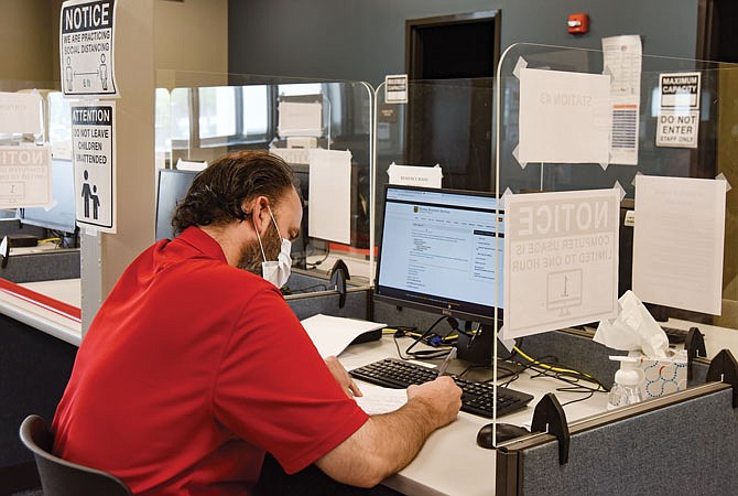 A man works at a computer station Friday at the Jefferson City office of Workforce Development. While he was filling out papers, a ribbon cutting ceremony was going on in the next room in the former Sears wing of the Capital Mall to celebrate the reopening of the Office of Workforce Development. 