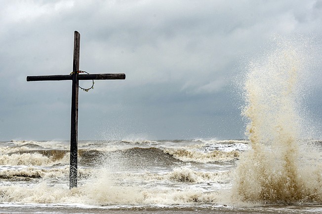 The cross that stands on the beach near highways 124 and 87 is buffeted by the high seas Sunday on Bolivar Peninsula, Texas. Tropical Storm Beta is expected this week to bring heavy rainfall to parts of the upper Texas Gulf Coast and Louisiana.