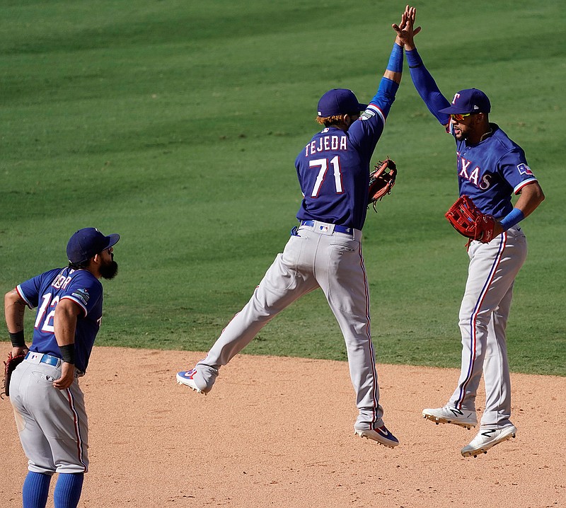 Texas Rangers shortstop Anderson Tejeda, center, leaps with center fielder Leody Taveras, right, as second baseman Rougned Odor watches after they defeated the Los Angeles Angels in a baseball game in Anaheim, Calif., Sunday, Sept. 20, 2020. (AP Photo/Alex Gallardo)