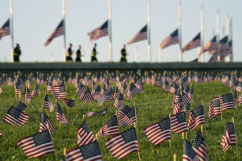 Activists from the COVID Memorial Project mark the deaths of 200,000 lives lost in the U.S. to COVID-19 after placing thousands of small American flags on the grounds of the National Mall in Washington, Tuesday, Sept. 22, 2020. (AP Photo/J. Scott Applewhite)