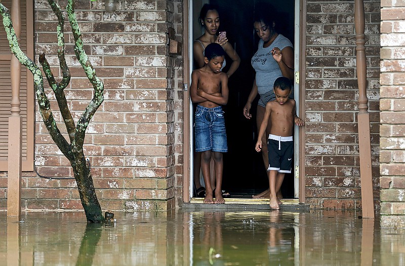 Eight-year-old Cam'ron Maltie, left, and Adrian Murray, 4, look at the their flooded front lawn during Tropical Storm Beta, Tuesday, Sept. 22, 2020, in Houston. Their family has been living in the home for a year and didn't know the neighborhood flooded. (Godofredo A. Vsquez/Houston Chronicle via AP)