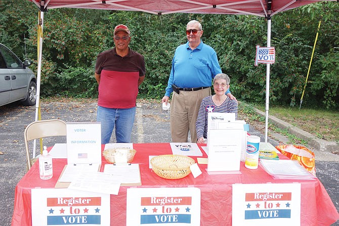 Don Glover, left, and Neal and Mary Powers staffed a voter registration booth Wednesday at the Fulton Farmers Market. The NAACP will also have a booth Saturday at the market.
