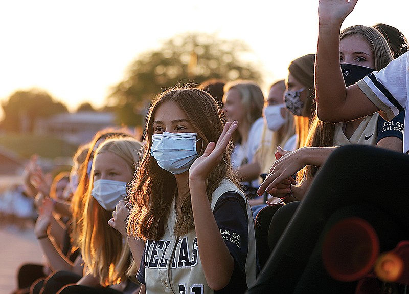 Helias softball player Natalie Schroeder greets passing cars Thursday while sitting on a long flat trailer bed during Helias' drive-through homecoming parade at Helias Catholic High School.