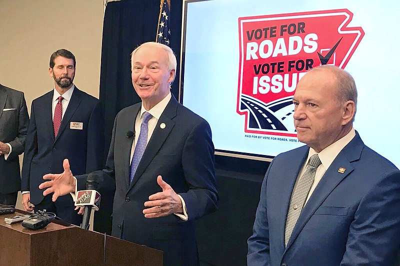 Arkansas Gov. Asa Hutchinson, center, speaks at a news conference Friday, Nov.  15, 2019, at the Poultry Federation in Little Rock about the campaign to extend a half-cent sales tax for highways. Hutchinson on Wednesday called the effort to keep the tax his top priority among this year's ballot initiatives. The half-cent tax approved by voters in 2012 is to expire in 2023 unless voters extend it by approving a ballot measure that is part of a highway funding package passed by the Legislature in 2019.