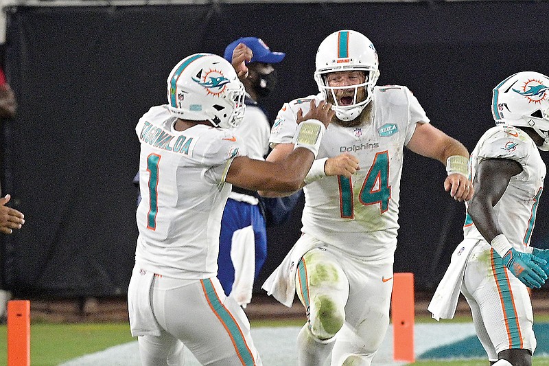 Dolphins quarterback Ryan Fitzpatrick celebrates with teammate Tua Tagovailoa after throwing a touchdown pass against the Jaguars during the first half of Thursday night's game in Jacksonville, Fla.