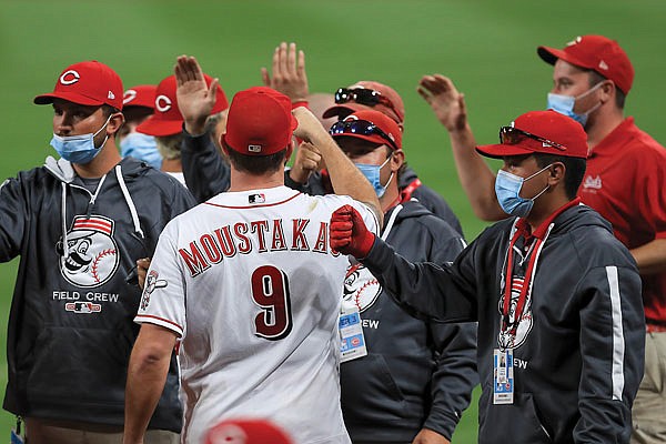Mike Moustakas of the Reds fist bumps members of the grounds crew after Wednesday's game against the Brewers in Cincinnati.