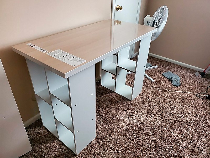 In this photo provided by Megan Fry, a desk Fry constructed out of a legless tabletop and bookcases stands in her Indianapolis home on Sept. 14, 2020. First it was toilet paper. Disinfectant wipes. Beans. Coins. Computers. Now, desks are in short supply because of the coronavirus pandemic. "It's not as cute or trendy as a bought desk and I wish it had drawers for storage," said Fry, who is starting a new work-from-home customer service job in Indianapolis in October.  "But I'm happy it's clean and has a large surface on top for my monitors and laptop." (Megan Fry via AP)