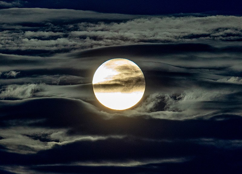 In this Sept. 2, 2020 file photo, the full moon shines surrounded by clouds in the outskirts of Frankfurt, Germany.  Future moon explorers will face ultrahazardous radiation levels. That's the conclusion of a new study published by Chinese and German scientists Friday, Sept. 25. The researchers say astronauts on the moon will be bombarded with two to three times more radiation than astronauts currently circling Earth aboard the International Space Station.(AP Photo/Michael Probst, File)