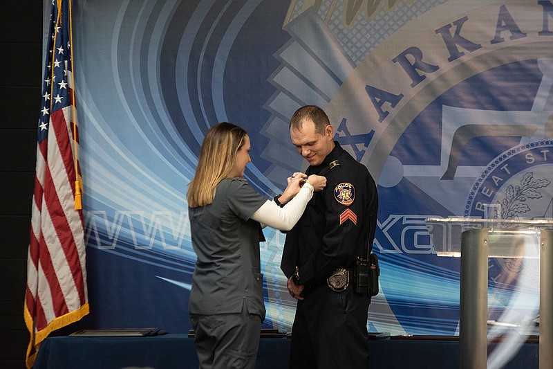 Elizabeth Tirone pins a badge on her husband, Nick Tirone, who was promoted to sergeant, at the Texarkana Texas Police Department's awards ceremony on Tuesday.