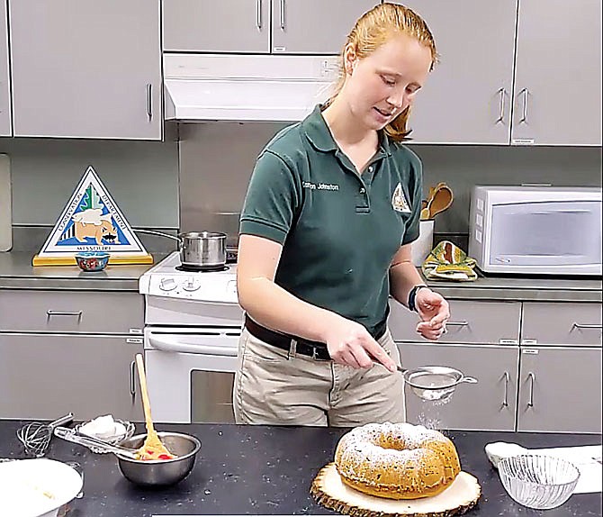 Missouri Department of Conservation naturalist Cameron Johnston sprinkles sugar on a persimmon cake.