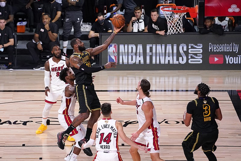 Lakers forward LeBron James goes up for a shot between Heat teammates Jimmy Butler (center left), Tyler Herro (14) and Kelly Olynyk (9) on Friday during the second half of Game 2 of the NBA Finals in Lake Buena Vista, Fla.