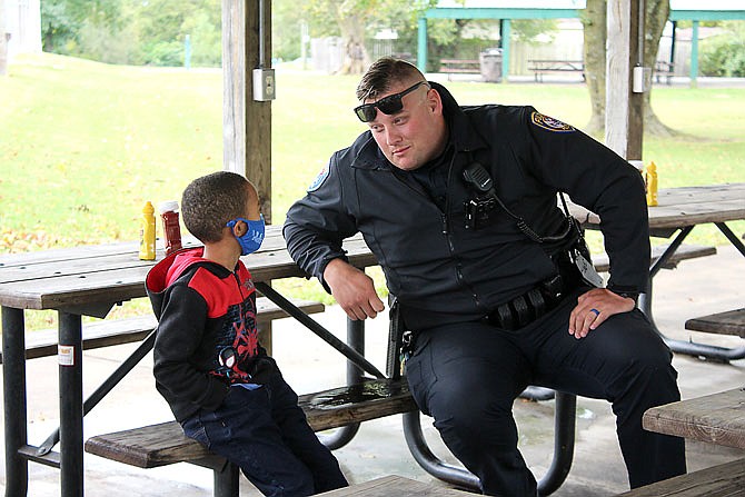 In this Oct. 3, 2020 photo, Fulton police officer Lance Reams greets a young visitor during a police meet and greet at Carver Park. (Fulton Sun photo)