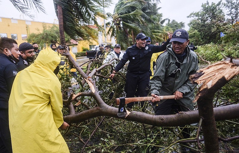Firemen remove a tree toppled by Hurricane Delta in Cancun, Mexico, early Wednesday, Oct. 7, 2020. Hurricane Delta made landfall Wednesday just south of the Mexican resort of Cancun as a Category 2 storm, downing trees and knocking out power to some resorts along the northeastern coast of the Yucatan Peninsula. (AP Photo/Victor Ruiz Garcia)