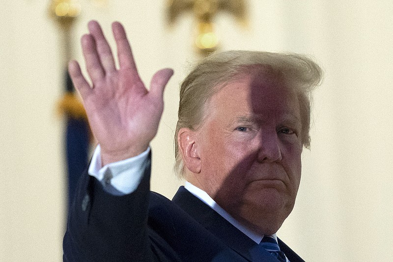 President Donald Trump waves from the Blue Room Balcony upon returning to the White House Monday, Oct. 5, 2020, in Washington, after leaving Walter Reed National Military Medical Center, in Bethesda, Md. Trump announced he tested positive for COVID-19 on Oct. 2. (AP Photo/Alex Brandon)