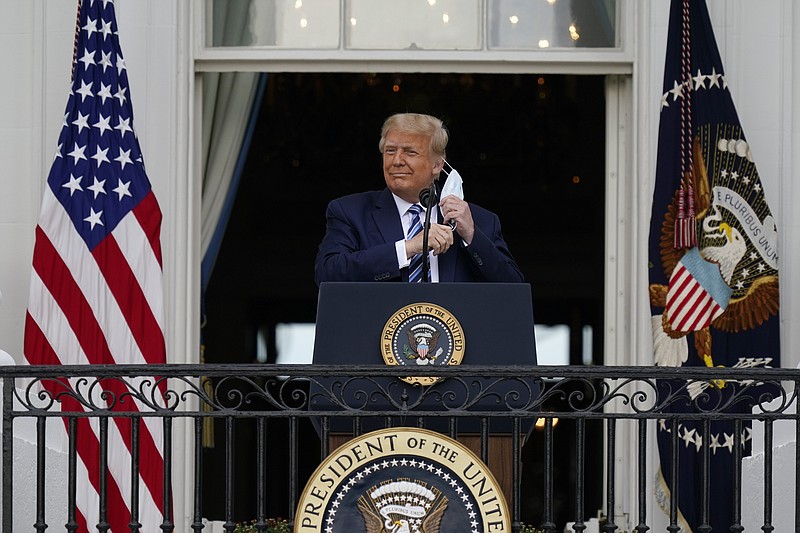 President Donald Trump removes his face mask to speak from the Blue Room Balcony of the White House to a crowd of supporters, Saturday, Oct. 10, 2020, in Washington. (AP Photo/Alex Brandon)