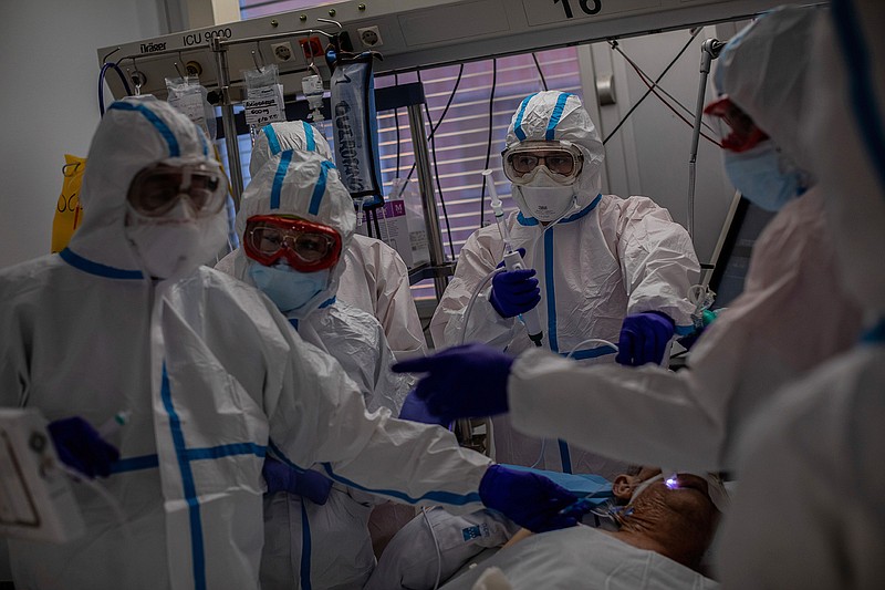 In this Oct. 9, 2020, file photo, a medical team treats a patient infected with COVID-19 in one of the intensive care units (ICU) at the Severo Ochoa hospital in Leganes, outskirts of Madrid, Spain. Europe's second wave of coronavirus infections has struck well before flu season even started. Intensive care wards are filling up again and bars are shutting down. (AP Photo/Bernat Armangue, File)