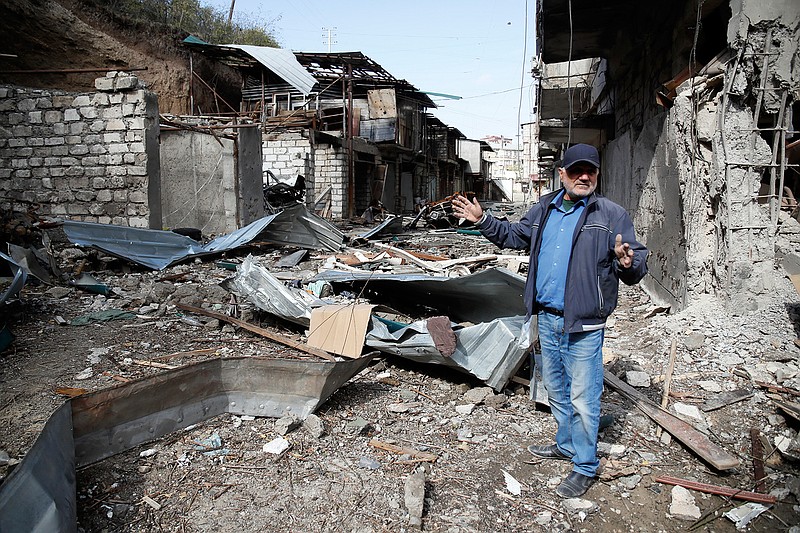 Eduard Chechyan gestures in the yard of his apartment building, destroyed by shelling by Azerbaijan's artillery, during a military conflict in Stepanakert, the separatist region of Nagorno-Karabakh, Saturday, Oct. 10, 2020. Armenia and Azerbaijan have agreed to a Russia-brokered cease-fire in Nagorno-Karabakh after two weeks of heavy fighting that marked the worst outbreak of hostilities in the separatist region in more than a quarter-century. (AP Photo)