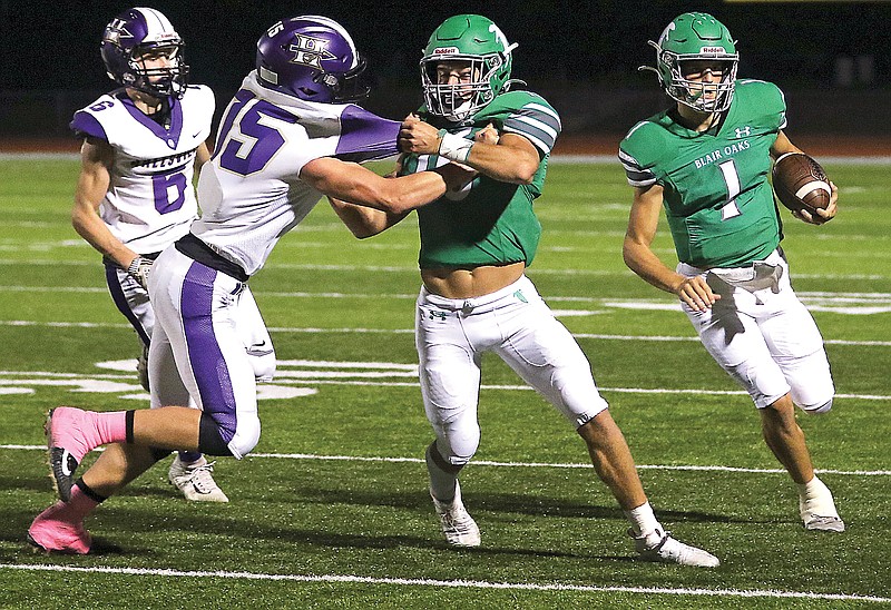 Blair Oaks quarterback Dylan Hair (right) runs toward the sideline while wide receiver Jake Closser (center) blocks Hallsville defensive back Ryan Roberts during Friday's Homecoming game at the Falcon Athletic Complex in Wardsville.