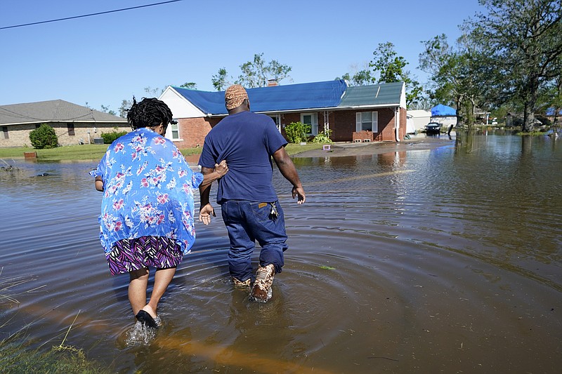 Soncia King holds onto her husband Patrick King in Lake Charles, Louisiana, on Saturday as they walk through the flooded street to their home, after Hurricane Delta moved through on Friday. (AP Photo/Gerald Herbert)