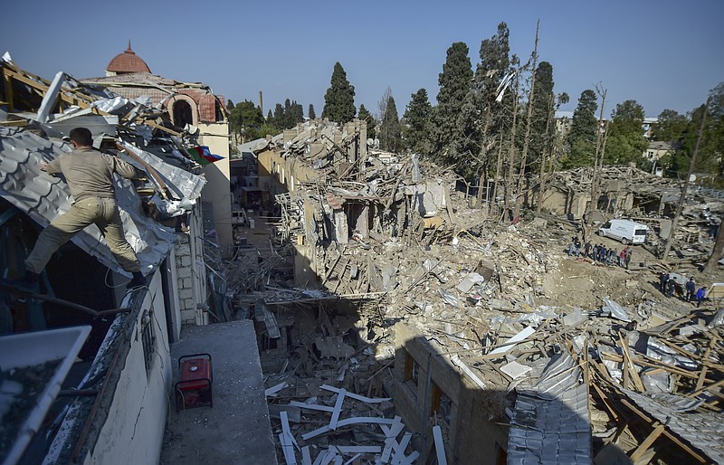 People look at the destroyed houses a day after shelling by Armenian's artillery during fighting over the separatist region of Nagorno-Karabakh, in Ganja, Azerbaijan, Monday, Oct. 12, 2020. Armenia and Azerbaijan on Monday have accused each other of attacks over the separatist territory of Nagorno-Karabakh despite a cease-fire deal brokered by Russia in an effort to end the worst outbreak of hostilities in decades. (AP Photo)