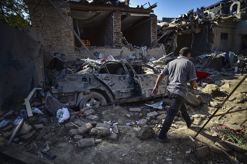 A man walks amongst the debris of damaged houses two days after shelling by Armenian's artillery during fighting over the separatist region of Nagorno-Karabakh, in Ganja, Azerbaijan, Tuesday, Oct. 13, 2020. Azerbaijan has accused Armenia of attacking large cities Sunday overnight in violation of the cease-fire deal brokered by Russia that seeks to end the worst outbreak of hostilities in the separatist Nagorno-Karabakh region. (Ismail Coskun/IHA via AP)