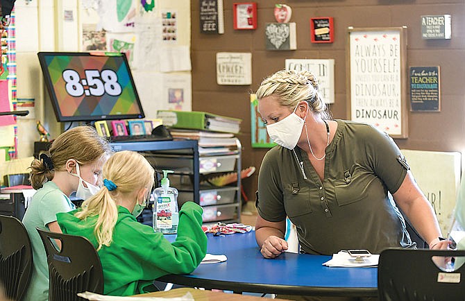 Brylee Bolton, left, and Ella Shade work closely with their second-grade teacher, Tori Berendzen, on Tuesday at Blair Oaks Elementary School. The Blair Oaks Board of Education approved a proposal to classify staff members as essential employees.