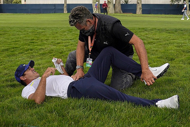 This Aug. 7, 2020, file photo shows Brooks Koepka getting treated for an injury on the 12th hole during the second round of the PGA Championship golf tournament at TPC Harding Park Friday, Aug. 7, 2020, in San Francisco. Koepka was out two months with a hip injury and returns this week at the CJ Cup at Shadow Creek in Las Vegas. (AP Photo/Jeff Chiu, File)