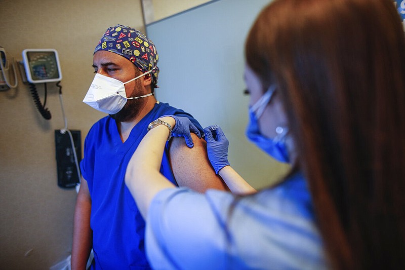 In this Oct. 9, 2020, file photo, a health worker, right, administers the first dose of a COVID-19 vaccine currently on phase III clinical trials to Cem Gun, an emergency medicine physician at the Acibadem Hospital in Istanbul. The World Bank has approved $12 billion in financing to help developing countries buy and distribute coronavirus vaccines, tests, and treatments, aiming to support the vaccination of up to 1 billion people, the bank said in a statement late Tuesday, Oct. 13. (AP Photo/Emrah Gurel, File)