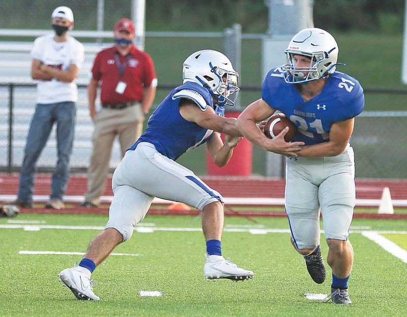 Capital City quarterback Kaden Dassrath hands the ball off to running back Ethan Wood during a 2020 game against Warrensburg at Adkins Stadium.