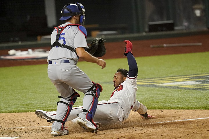 Atlanta Braves' Ozzie Albies scores past Los Angeles Dodgers catcher Austin Barnes on a double by Dansby Swanson during the sixth inning in Game 4 of a baseball National League Championship Thursday, Oct. 15, 2020, in Arlington, Texas. (AP Photo/Eric Gay)