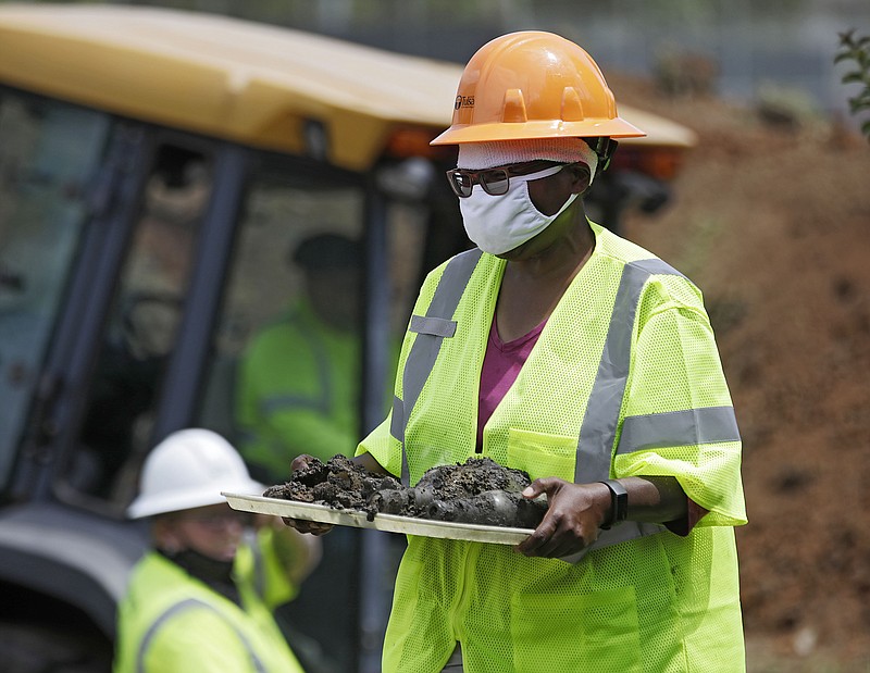 FILE - In this July 21, 2020, file photo, forensic anthropologist Phoebe Stubblefield carries a tray of items found at Oaklawn Cemetery during a test excavation in the search for possible mass graves from the 1921 Tulsa Race Massacre in Tulsa, Okla. A second excavation begins Monday, Oct. 19, 2020 at a Tulsa cemetery in search of people killed in the massacre in an effort to identify the victims and shed light on the violence. (Mike Simons/Tulsa World via AP File)