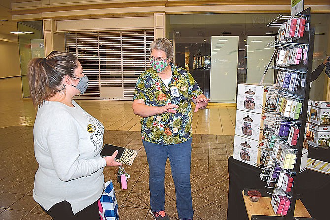 Barb Willems, right, co-owner of COMO Scents and More, talks to Jessica Porter about the products offered by the business at Sunday's Capital Mall Trade Days.
