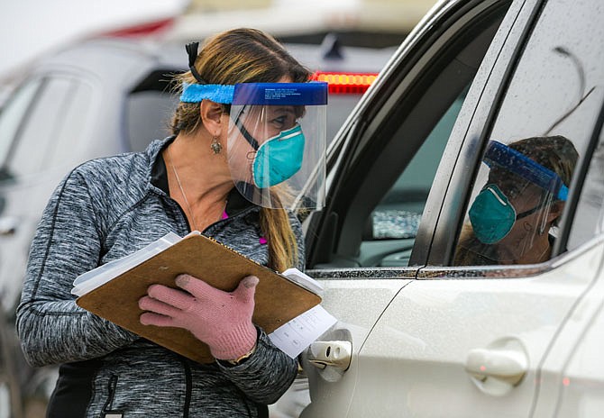 Diane Palms gets the necessary information from an individual who is in line Monday for COVID-19 testing at Capital Region Medical Center.