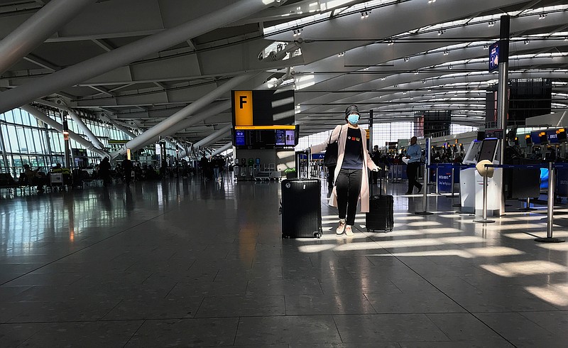In this Tuesday, March 24, 2020 file photo, a woman wears a mask as she walks through a quieter than usual Heathrow Airport Terminal 5, in London. Air traffic is down 92% this year as travelers worry about catching COVID-19 and government travel bans and quarantine rules make planning difficult. One thing airlines believe could help is to have rapid virus tests of all passengers before departure. (AP Photo/Kirsty Wigglesworth, File)