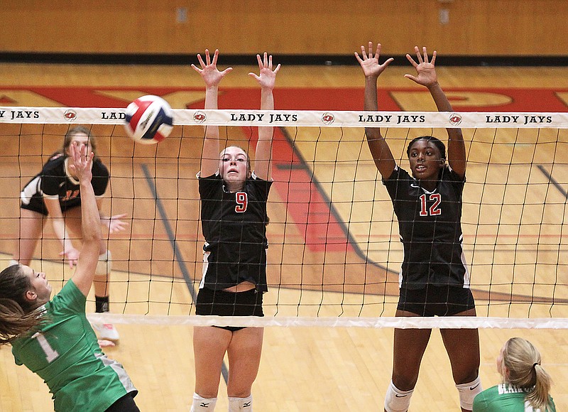 Jefferson City's Paige Reeser (9) and Rhakala Blackmon (12) go up for a block as Blair Oaks' Kennedy Flanner (far left) hits the ball during the first set of Tuesday's volleyball match at Fleming Fieldhouse.