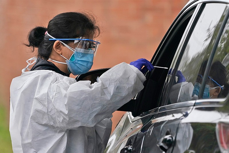 Medical personnel prepare to administer a COVID-19 swab at a drive-through testing site in Lawrence, N.Y., Wednesday, Oct. 21, 2020.  U.S. health officials are redefining what it means to have close contact with someone with COVID-19. On Wednesday, the CDC changed it to a total of 15 minutes or more, so briefer but repeated contacts that add up to 15 minutes now count.  (AP Photo/Seth Wenig)