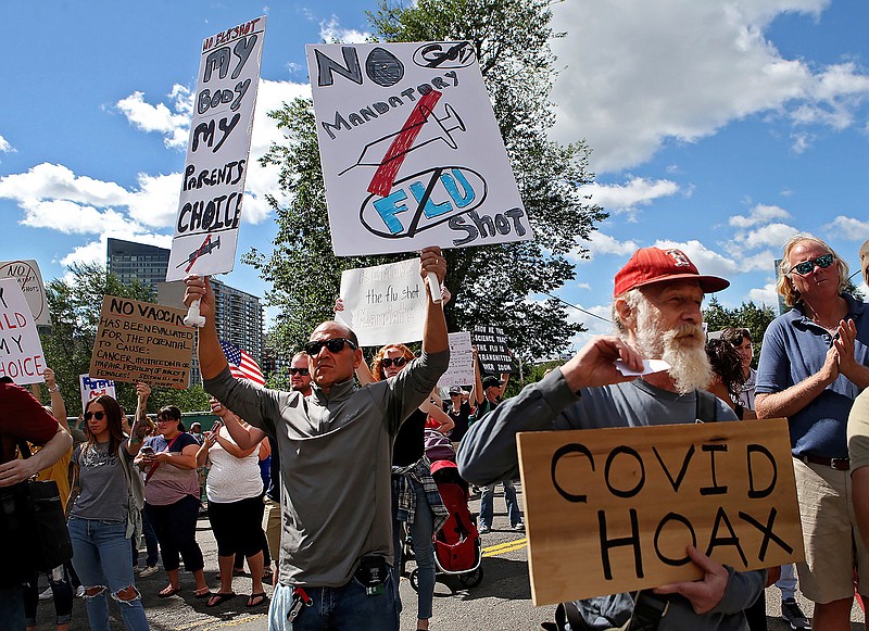 In this Aug. 30, 2020 file photo, Sal Lando, left, of Sterling, holds up signs during a protest against mandatory flu vaccinations, outside the Massachusetts State House, in Boston. Years before this year's anti-mask and reopening demonstrations, vaccine opponents were working on reinventing their image around a rallying cry of civil liberties and medical freedom. Now, boosted by the pandemic and the political climate, their rebranding is appealing to a different subset of society invested in civil liberties — and, some health officials say, undercutting public health efforts during a critical moment for vaccines. (Nancy Lane/Boston Herald via AP, File)