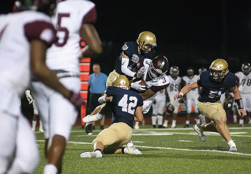 Helias teammates Drew Higgins and Ethan Holzhauser (42) go high and low to tackle Cardinal Ritter wide receiver Luther Burden III during a game last season at Ray Hentges Stadium.