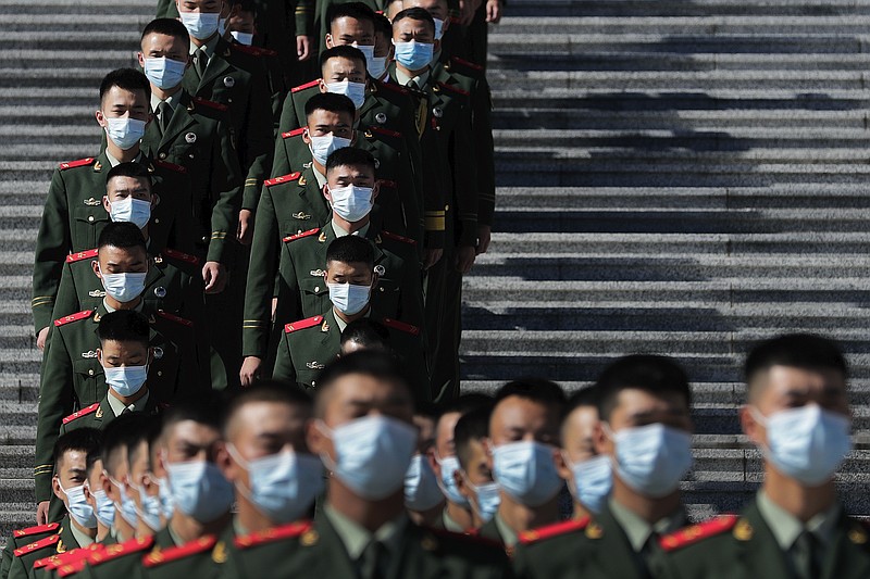 Chinese paramilitary policemen wearing face masks to help curb the spread of the coronavirus march down a staircase outside the Great Hall of the People after attending the commemorating conference on the 70th anniversary of China's entry into the 1950-53 Korean War, in Beijing Friday, Oct. 23, 2020. (AP Photo/Andy Wong)