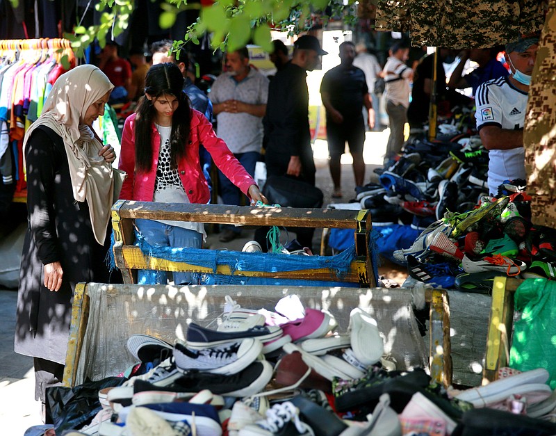 People shop for clothing at the used-clothes market in Baghdad, Iraq, Tuesday, Oct. 20, 2020.  Iraq is in the throes of an unprecedented liquidity crisis, as the cash-strapped state wrestles to pay public sector salaries and import essential goods while oil prices remain dangerously low. (AP Photo/Khalid Mohammed)