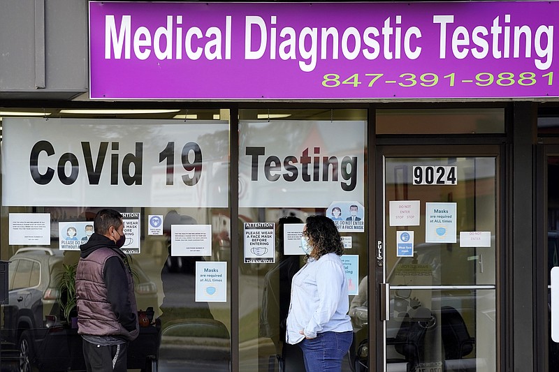 FILE - In this Oct. 21, 2020, file photo, Exam Corp Lab employee, right, wears a mask as she talks with a patient lined up for COVID-19 testing in Niles, Ill. The United States is approaching a record for the number of new daily coronavirus cases in the latest ominous sign about the disease's grip on the nation. (AP Photo/Nam Y. Huh, File)