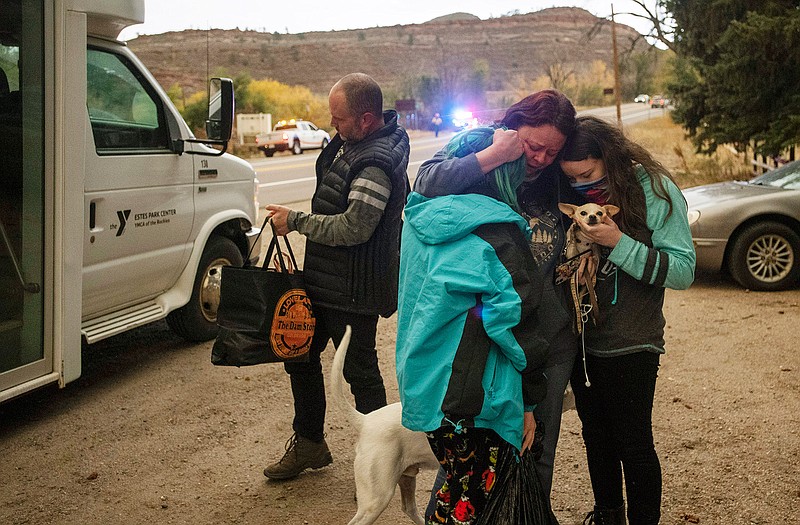 Melanie Luther embraces her two daughters Julie and Alex after reuniting with them and her husband Bryan Luther after all three were stranded in Estes Park when the city was evacuated due to the East Troublesome Fire, now the second largest in Colorado history, at The Dam Store along U.S. Highway 34 near Loveland, Colo., on Thursday, Oct. 22, 2020. (Bethany Baker/The Coloradoan via AP)