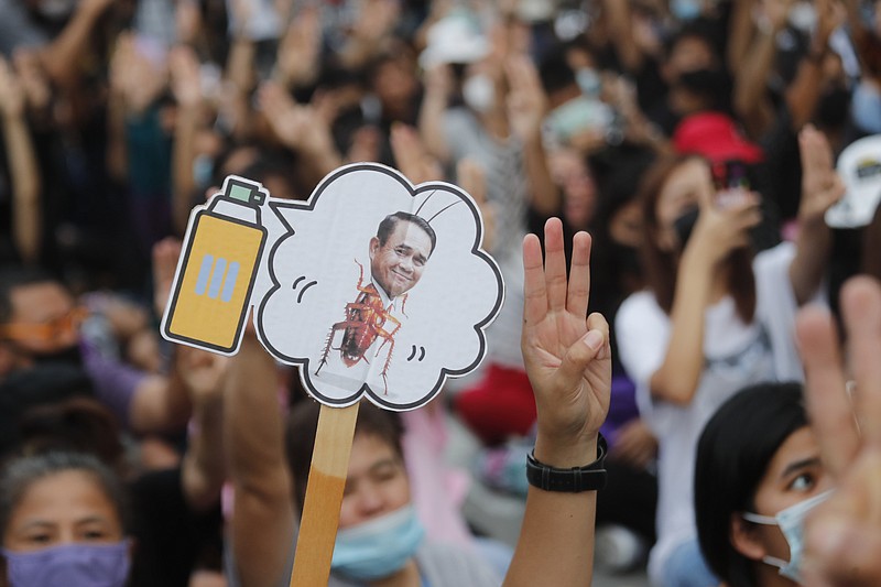 Pro-democracy activists display a placard with Thai Prime Minister Prayuth Chan-ocha's head attached to a cockroach during a protest outside remand prison, in which some of the activists are kept, in Bangkok, Thailand, Friday, Oct. 23, 2020. Thailand's government on Thursday canceled a state of emergency it had declared last week for Bangkok in a gesture offered by the embattled prime minister to cool student-led protests seeking democracy reforms. (AP Photo/Sakchai Lalit)
