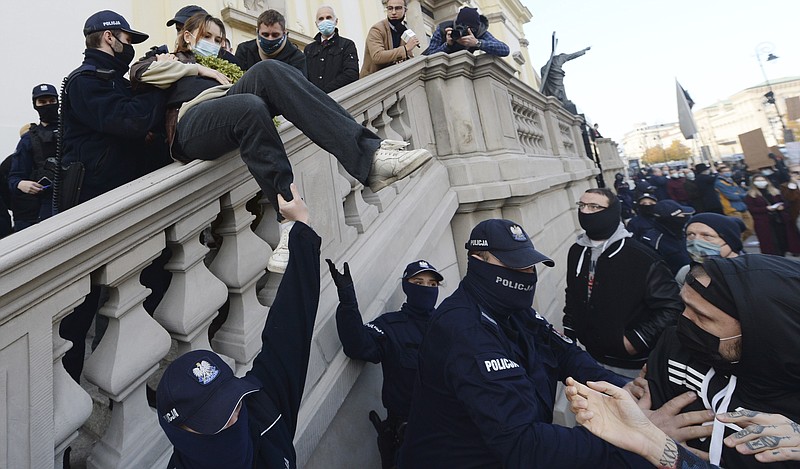 Members of a far-right organization and police remove women from a church where they were protesting church support for tightening Poland's already restrictive abortion law in Warsaw, Poland, Sunday, Oct. 25, 2020. Poland constitutional court issued a ruling on Thursday that further restricts abortion rights in Poland, triggering four straight days of protests across Poland.(AP Photo/Czarek Sokolowski)