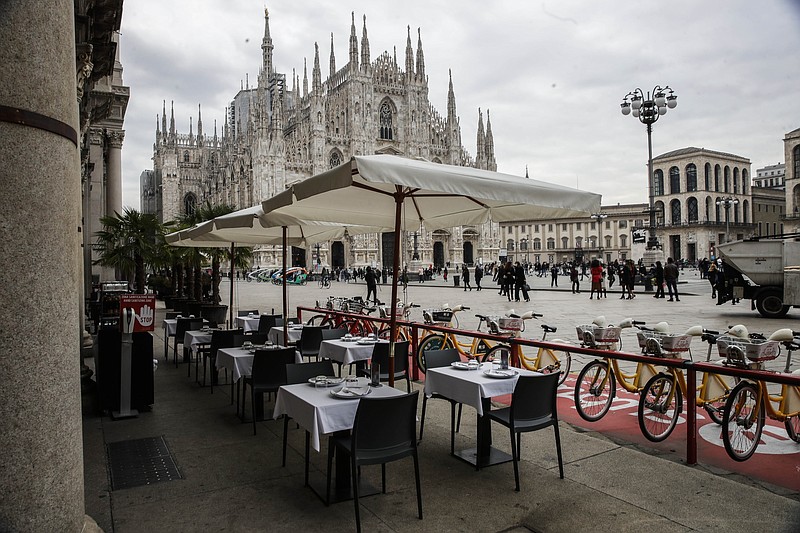 FILE - In this Wednesday, Oct. 21, 2020 file photo, empty tables of a restaurant in the Duomo Square in Milan, Italy. The coronavirus pandemic is gathering strength again in Europe and, with winter coming, its restaurant industry is struggling. The spring lockdowns were already devastating for many, and now a new set restrictions is dealing a second blow. Some governments have ordered restaurants closed; others have imposed restrictions curtailing how they operate.  (AP Photo/Luca Bruno, File)