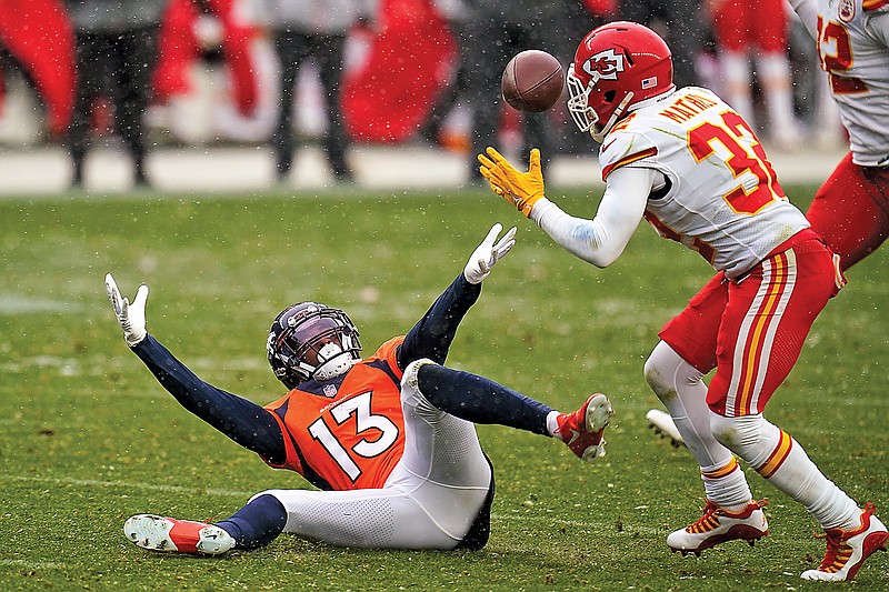 Broncos wide receiver K.J. Hamler (13) falls as Chiefs strong safety Tyrann Mathieu intercepts a pass during the second half of Sunday's game in Denver.