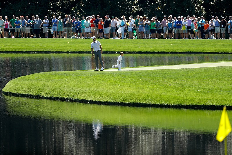 In this April 10, 2019, file photo, Dustin Johnson and son Tatum stand on the ninth green during the par-3 golf tournament at the Masters in Augusta, Ga. The Par 3 Contest is out at the spectator-free Masters in November. ESPN's "College GameDay" is in. Augusta National announced Tuesday, Oct. 27, 2020, more changes to a Masters tournament that will be unlike any of the previous 83. The most unusual of all is ESPN's popular college football pregame show taking place on a stage that overlooks Ike's Pond and the ninth green of the Par 3 course. (AP Photo/Matt Slocum, File)