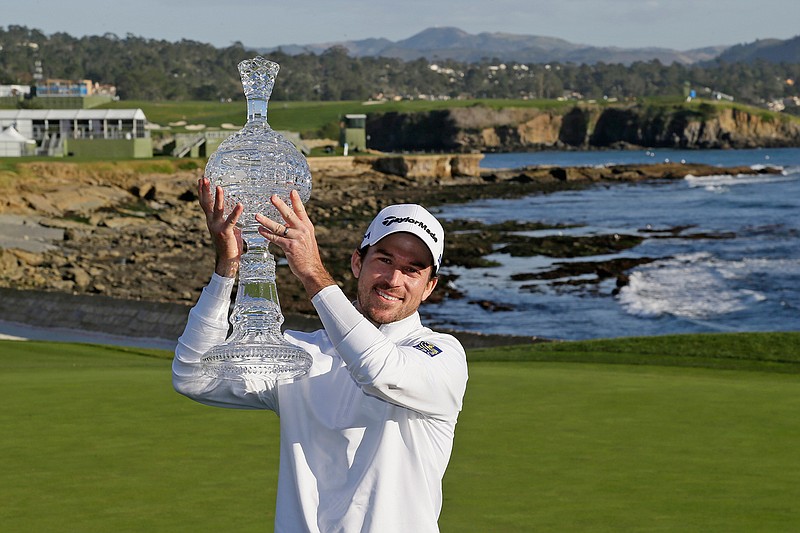 In this Feb. 9, 2020, file photo, Nick Taylor, of Canada, holds up his trophy on the 18th green of the Pebble Beach Golf Links after winning the AT&T Pebble Beach National Pro-Am golf tournament in Pebble Beach, Calif. The win got him into his first Masters, but Taylor will miss out on the roars without spectators. (AP Photo/Eric Risberg, File)